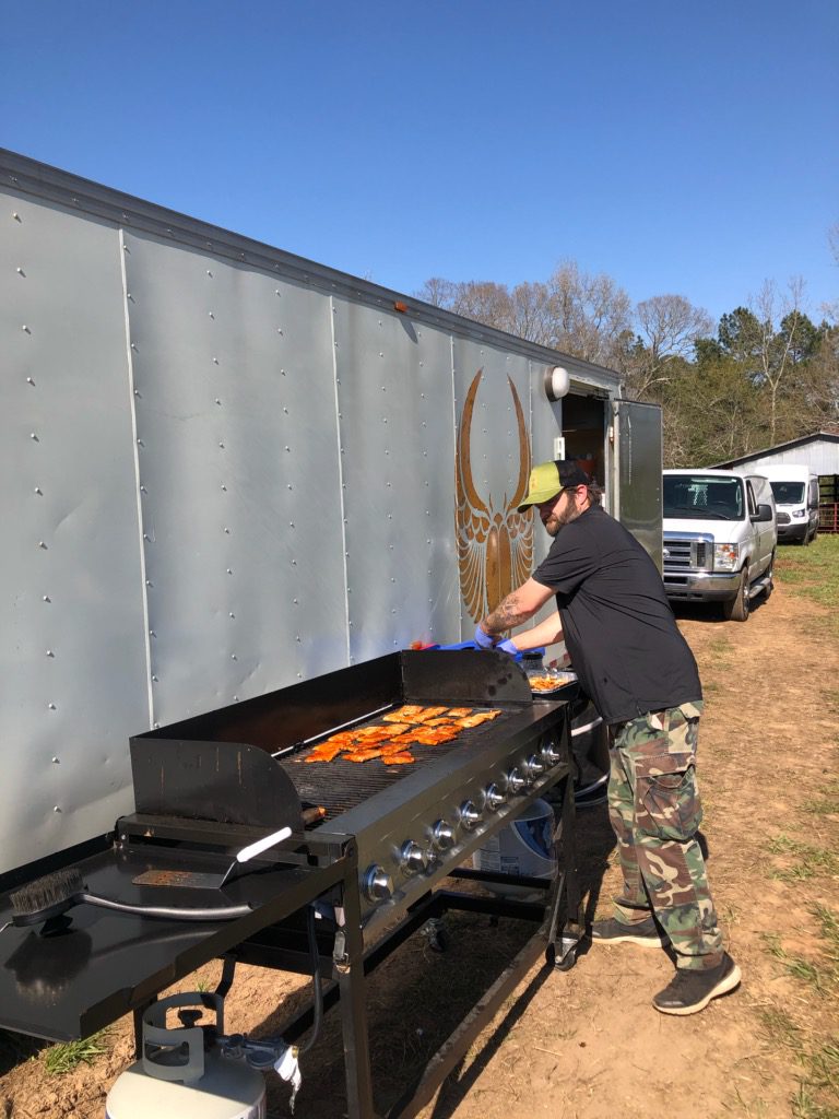 A man is cooking food on an outdoor grill.