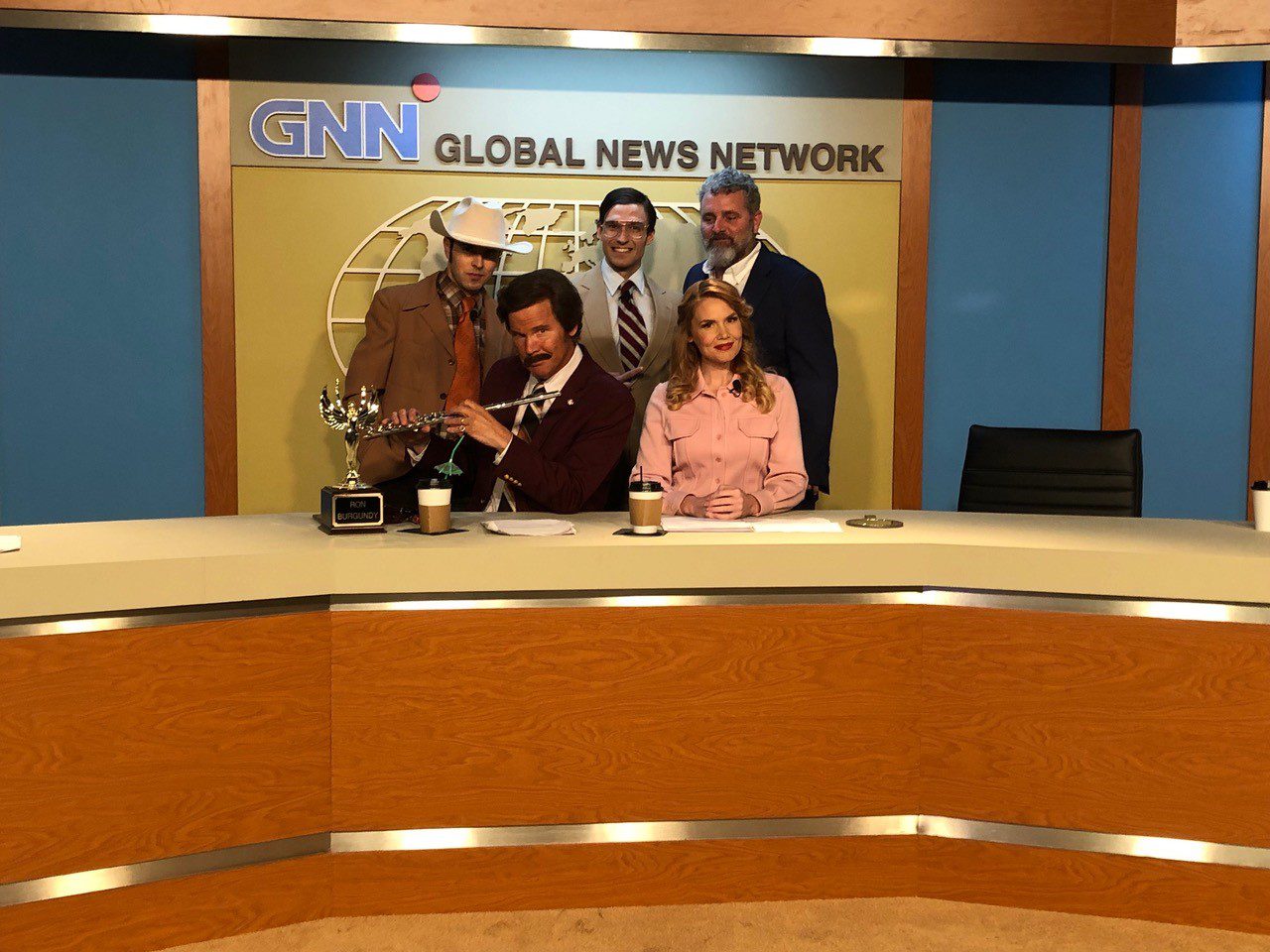 A group of people sitting in front of a news desk.